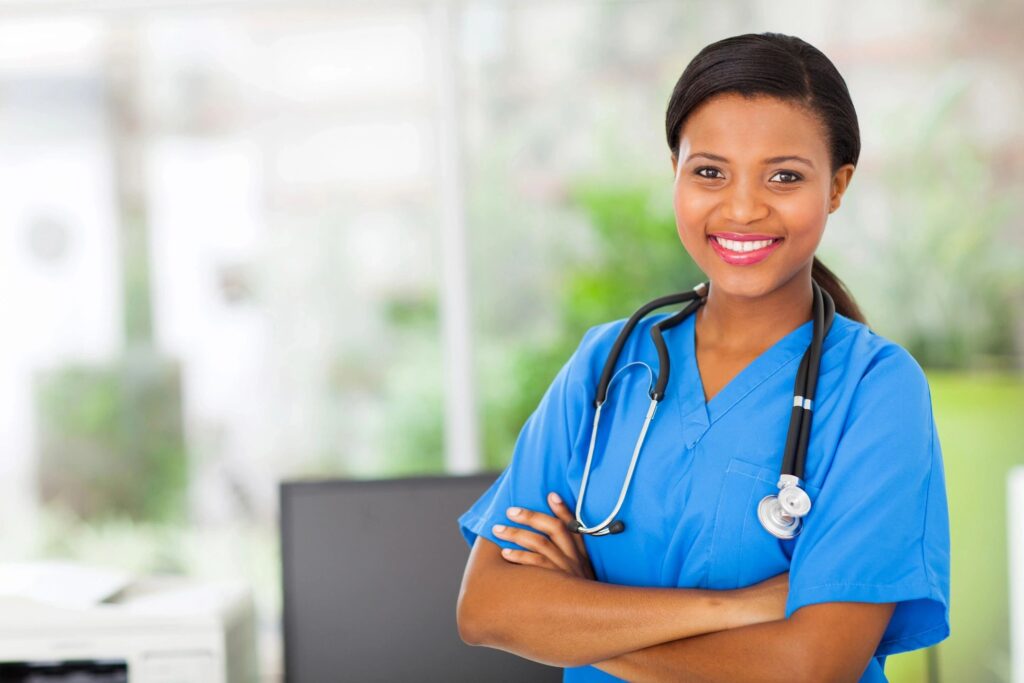 A woman in blue scrubs with her arms crossed.