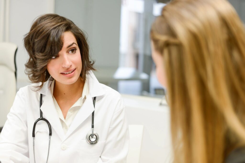 A woman in white coat sitting next to another person.