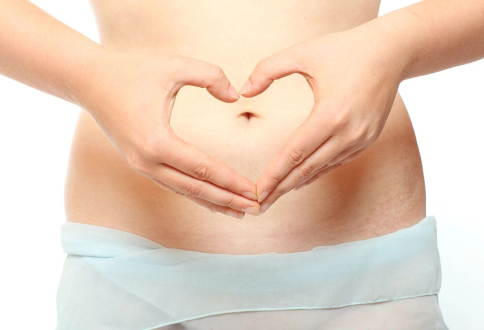 A woman forming a heart shape with her hands above her belly