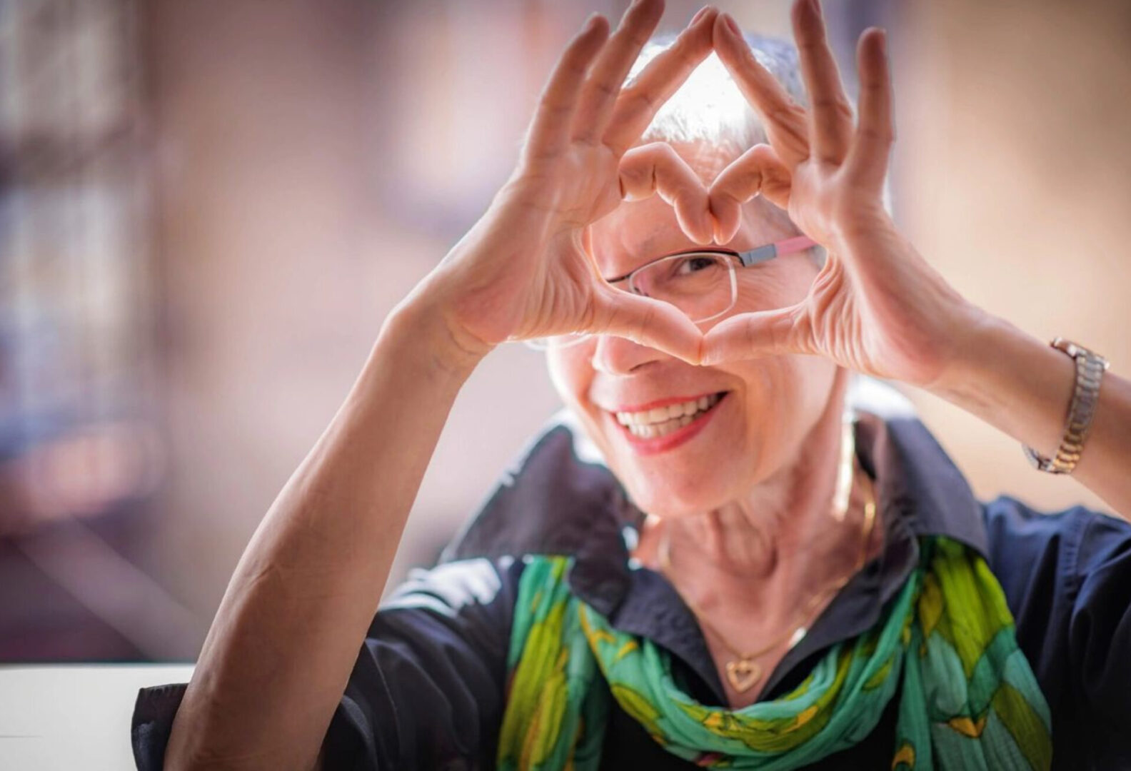 a woman looking through a heart shape made from fingers